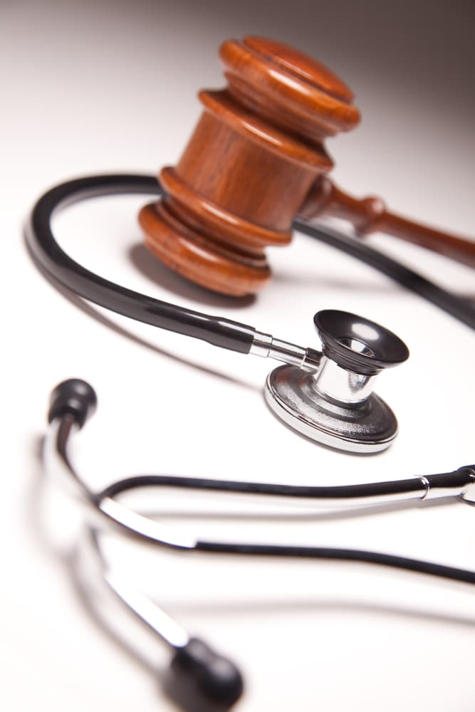 Selective focus on a gradated background, showcasing a gavel and stethoscope in juxtaposition.