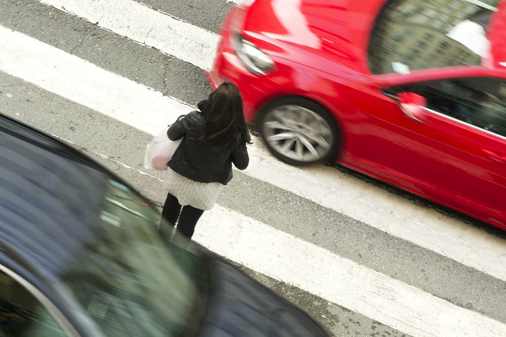 Woman navigating a precarious crosswalk amidst city traffic, emphasizing the importance of pedestrian safety and traffic awareness.