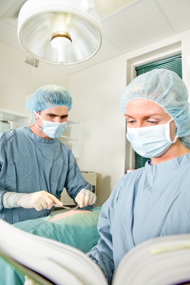 A surgeon navigating uncertainty during a procedure, consulting a manual for guidance in the operating room.