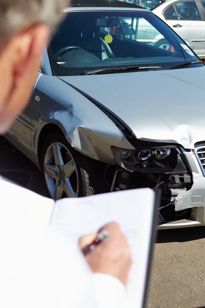 Insurance adjuster assessing the damages after a car accident.
