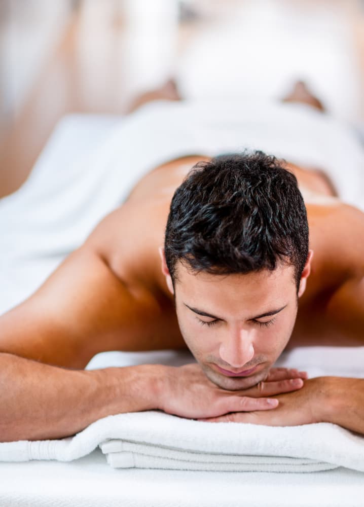 Man lying face down, relaxed on a massage table, awaiting a professional massage therapy session.