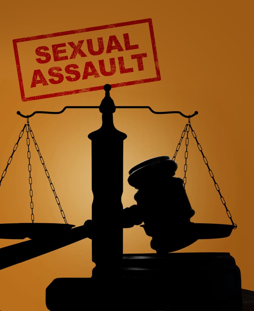 Silhouette of justice scales and gavel with a stamp reading "SEXUAL ASSAULT"
