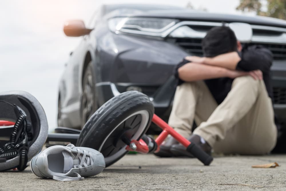 An accident scene with a comforting embrace, a car, a fallen electric scooter, and a shoe.