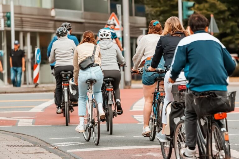 Many cyclists cross streets and intersections at traffic lights, following road safety rules and signals.