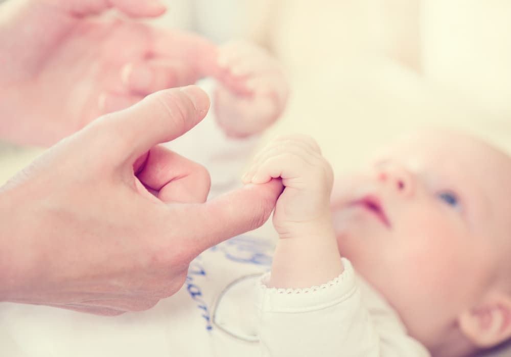 Parent gently holding a newborn’s hand — a tender moment of connection between mother and baby, symbolizing love, care, and the beginning of a lifelong bond.