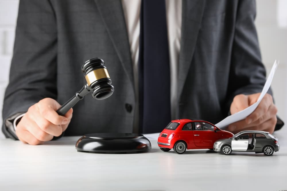 Car accident law concept. Close-up of a lawyer indoors, striking a gavel over documents on a table.