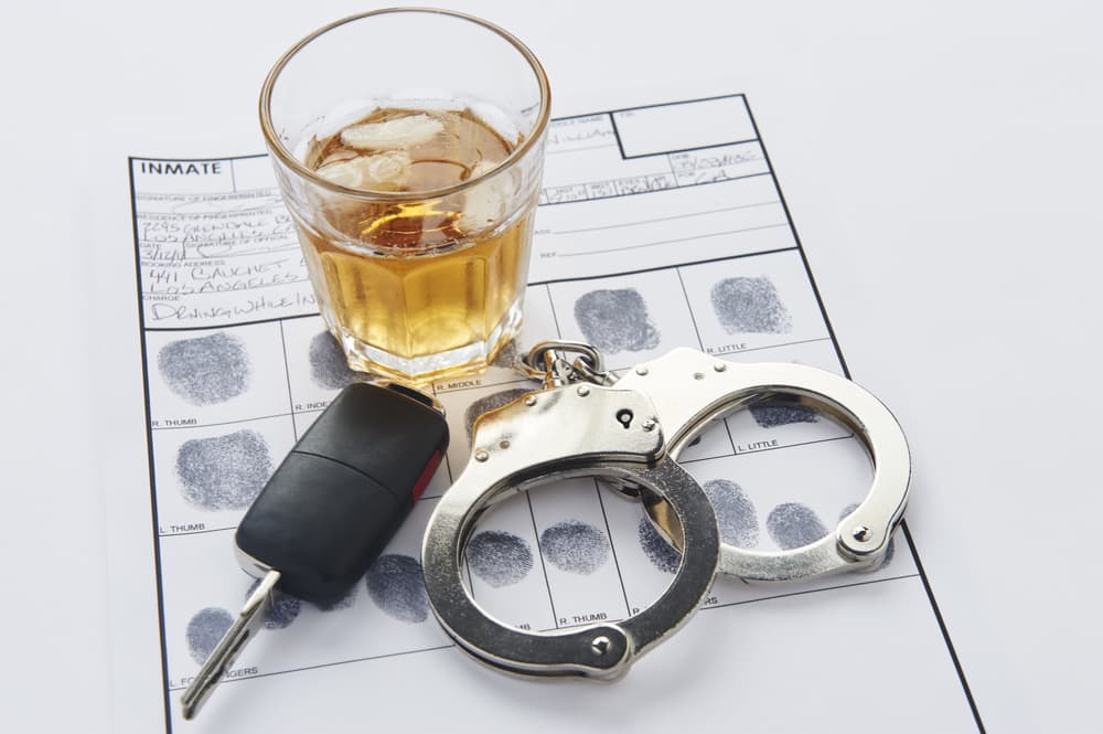Handcuffs, a glass of whiskey, and car keys placed over fingerprint evidence.