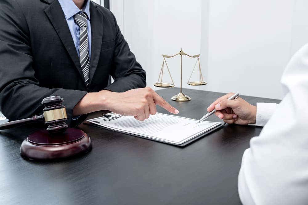 A male lawyer or judge advising clients on justice and prosecution. Legal services concept with scales of justice, gavel, and legal documents on the table.