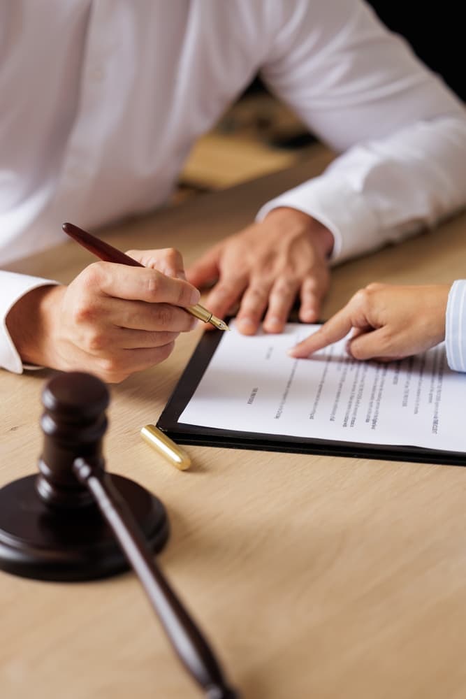 Consultation and discussion between a stressed businesswoman and legal professionals at a law firm office. Legal concepts shown with judge's gavel and scales of justice.