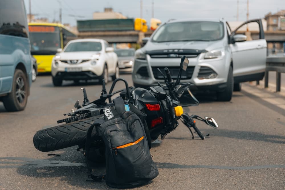 A motorcycle lies wrecked on the sidewalk after a serious crash. Close-up of the scene shows signs of a loss of control or possible collision with another vehicle.