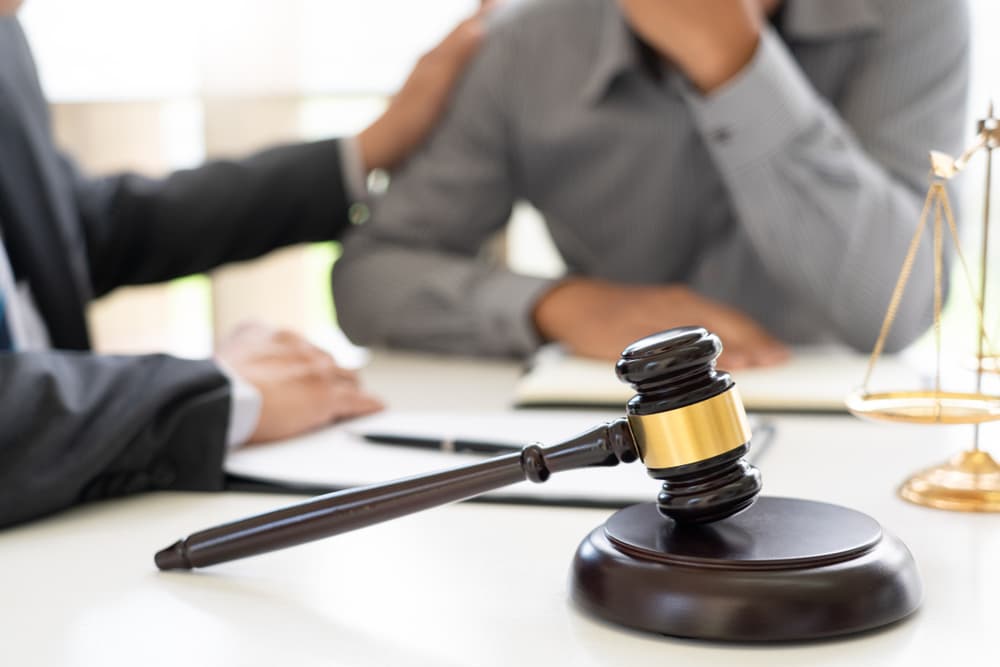 A lawyer meets with clients, offering legal advice with empathy and commitment. The scene reflects trust, serious discussion, and a shared pursuit of justice.