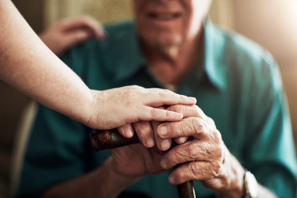 Elderly man and woman holding hands in a nursing home, symbolizing support, care, and compassion in assisted living.