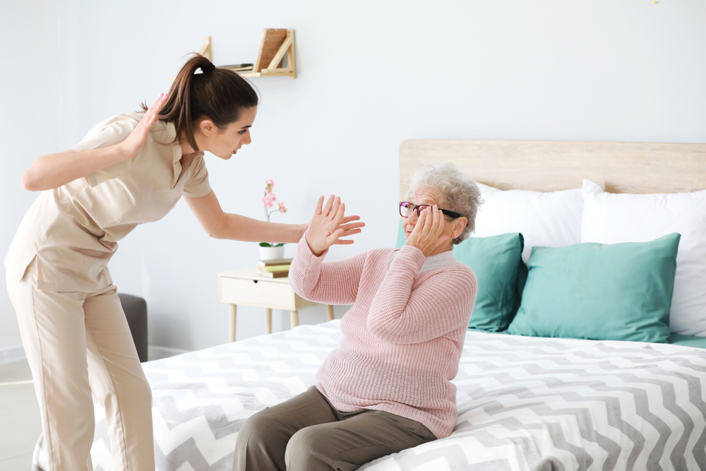 Senior woman facing mistreatment by caregiver in nursing home.