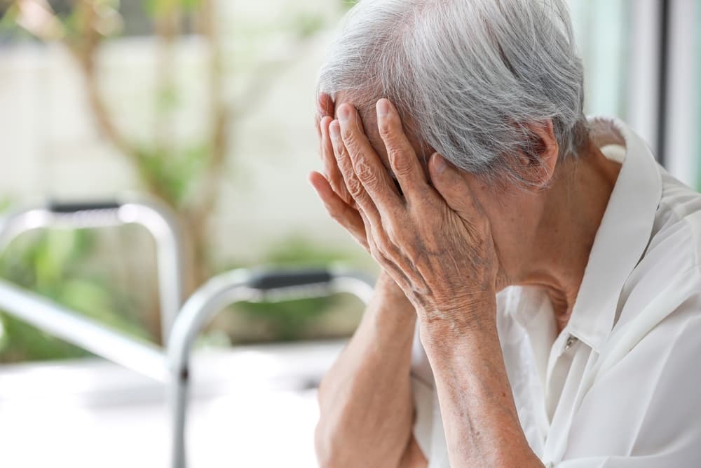 Depressed senior woman struggling with anxiety, emotional distress, and mood disorder, sitting alone at home and coping with the effects of mental illness.