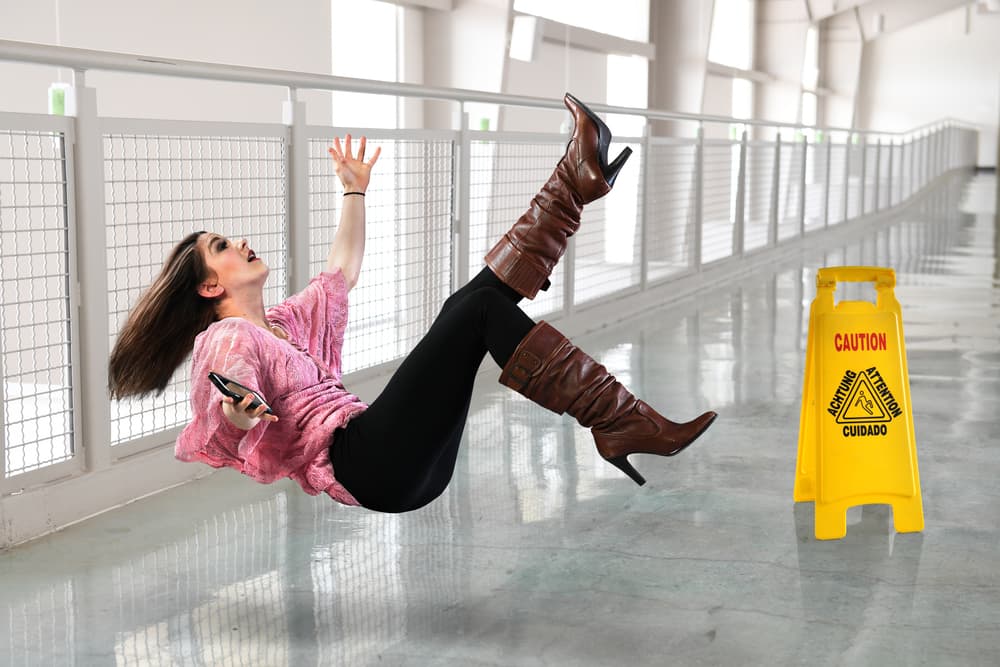Young professional woman slipping and falling on the floor inside an office building.