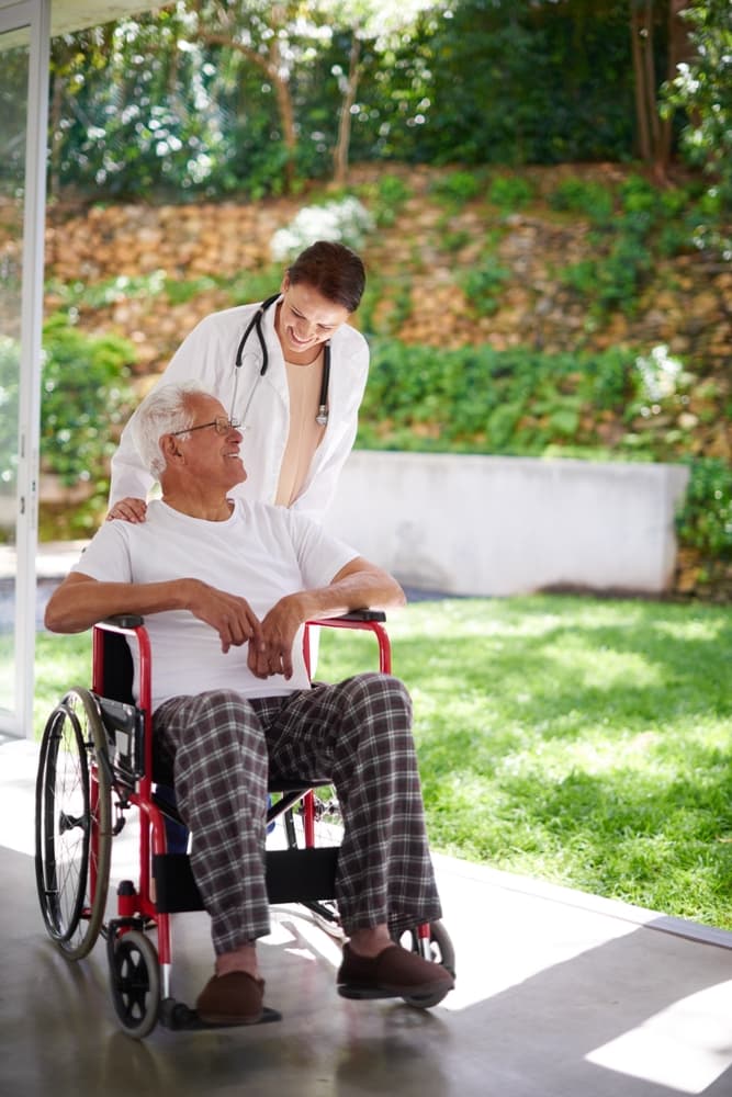 Doctor, woman assisting man in wheelchair at nursing home—offering support, care, and compassion during rehabilitation for injury or disability.